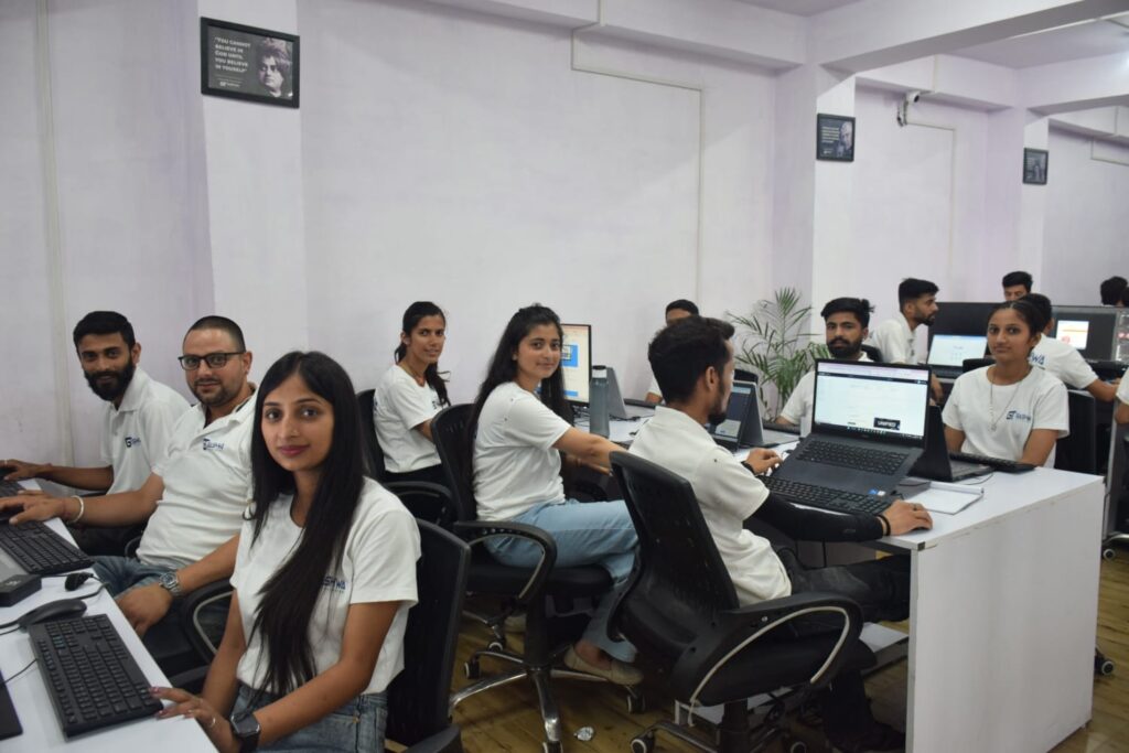 A group of Gashwa Institute of Technical Education employees working diligently at their desks with computers in a modern office setting.
