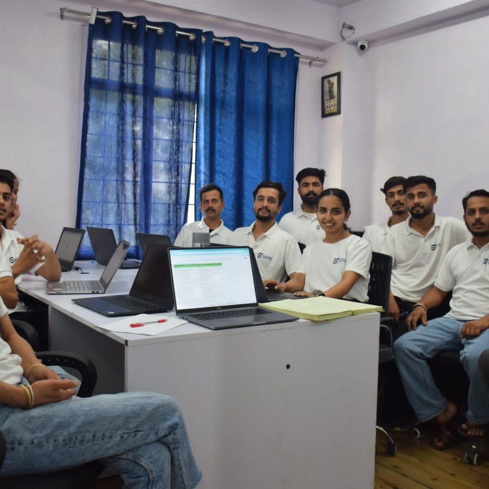 A group of professionals seated at a desk with laptops in the conference room of Gashwa Technologies during a meeting.