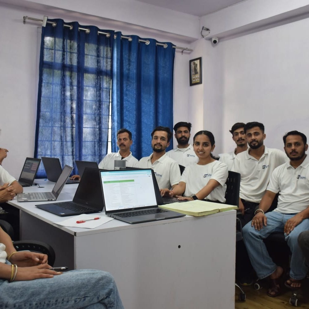 A group of professionals seated at a desk with laptops in the conference room of Gashwa Technologies during a meeting.