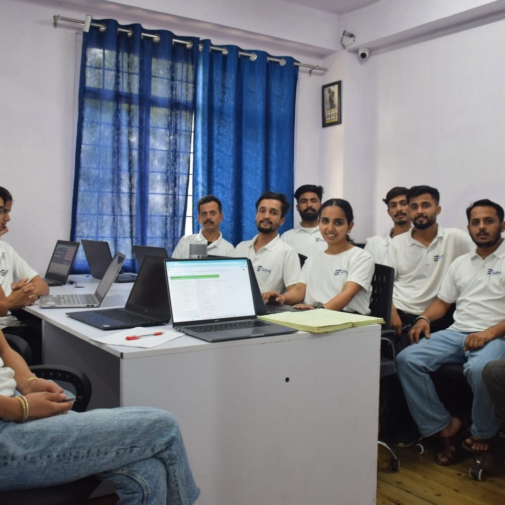 A group of professionals seated at a desk with laptops in the conference room of Gashwa Technologies during a meeting.