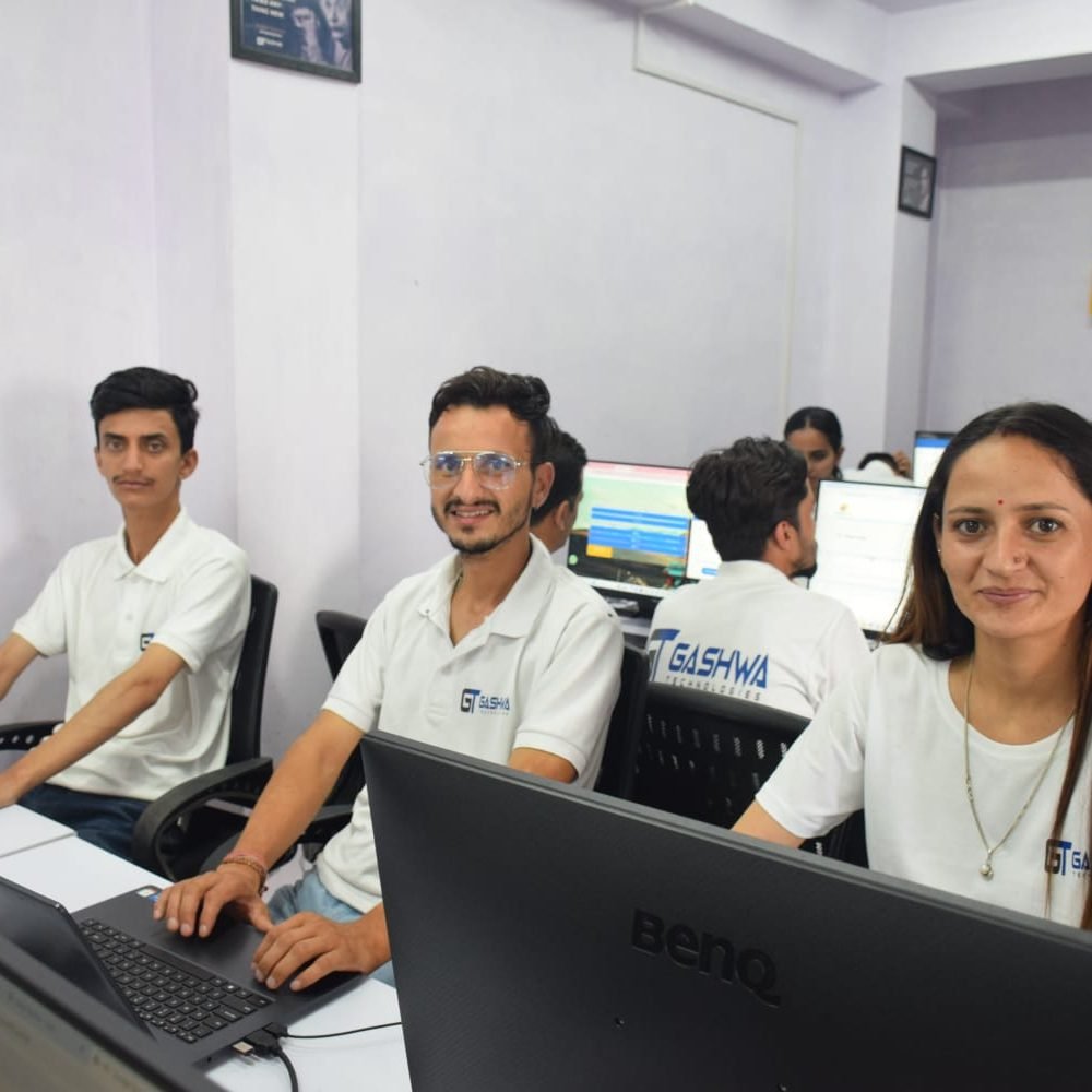 Employees of Gashwa Technologies focused on their tasks while seated at computers in a collaborative workspace.