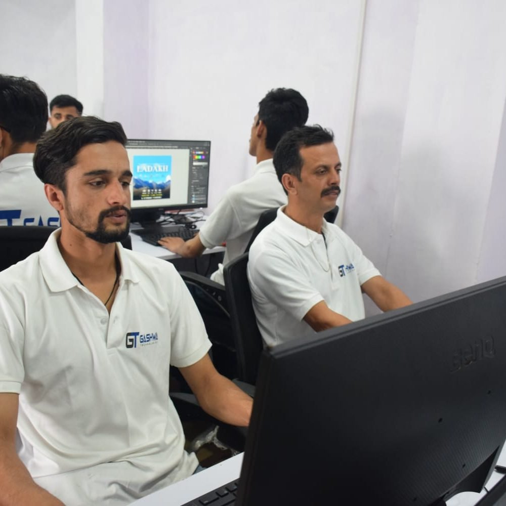 Gashwa Technologies staff members in white shirts seated at computers, collaborating on projects in a contemporary office.