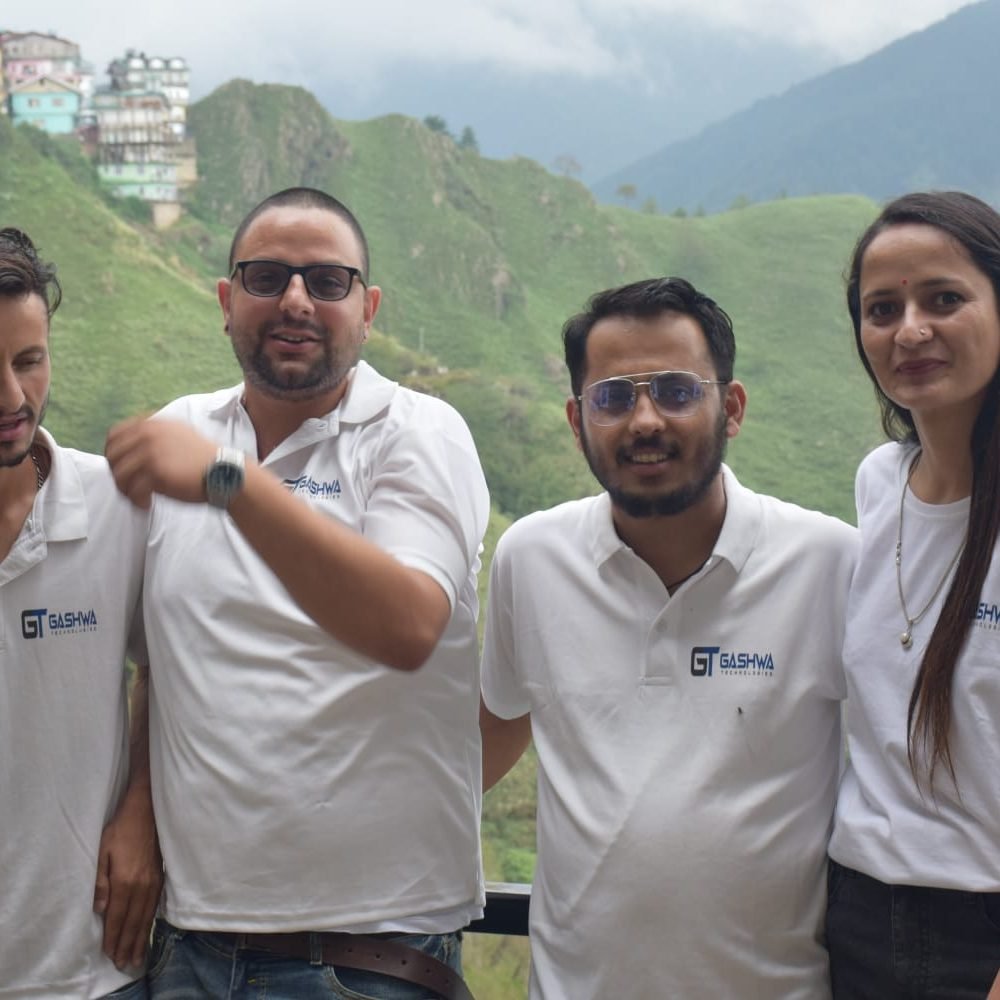 Four individuals in white shirts stand on a mountain, embodying unity and progress at Gashwa Technologies Private Limited.